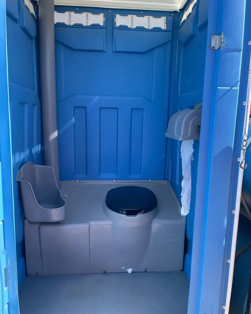 Toilet paper dispenser inside a standard porta potty stocked for a same-day rental in Midland, TX