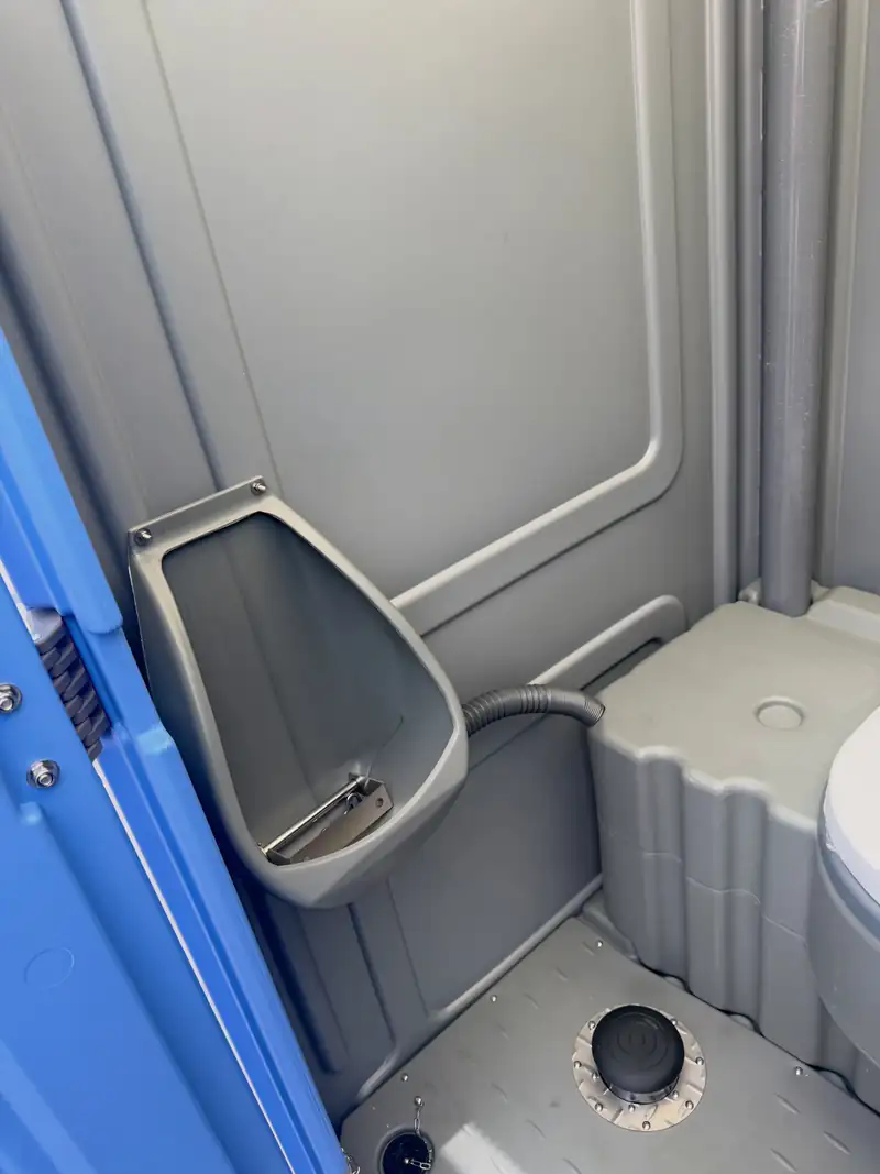 Urinal inside a standard porta potty serviced on route for a crew housing site near Midland, TX