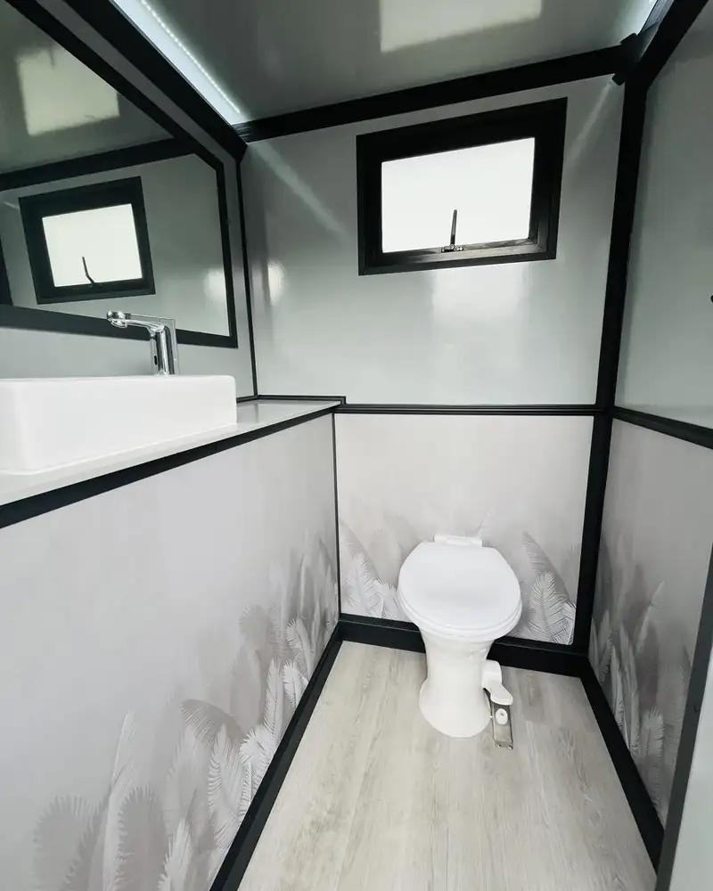 Restroom trailer stall interior with flushing toilet at an event in Midland, TX