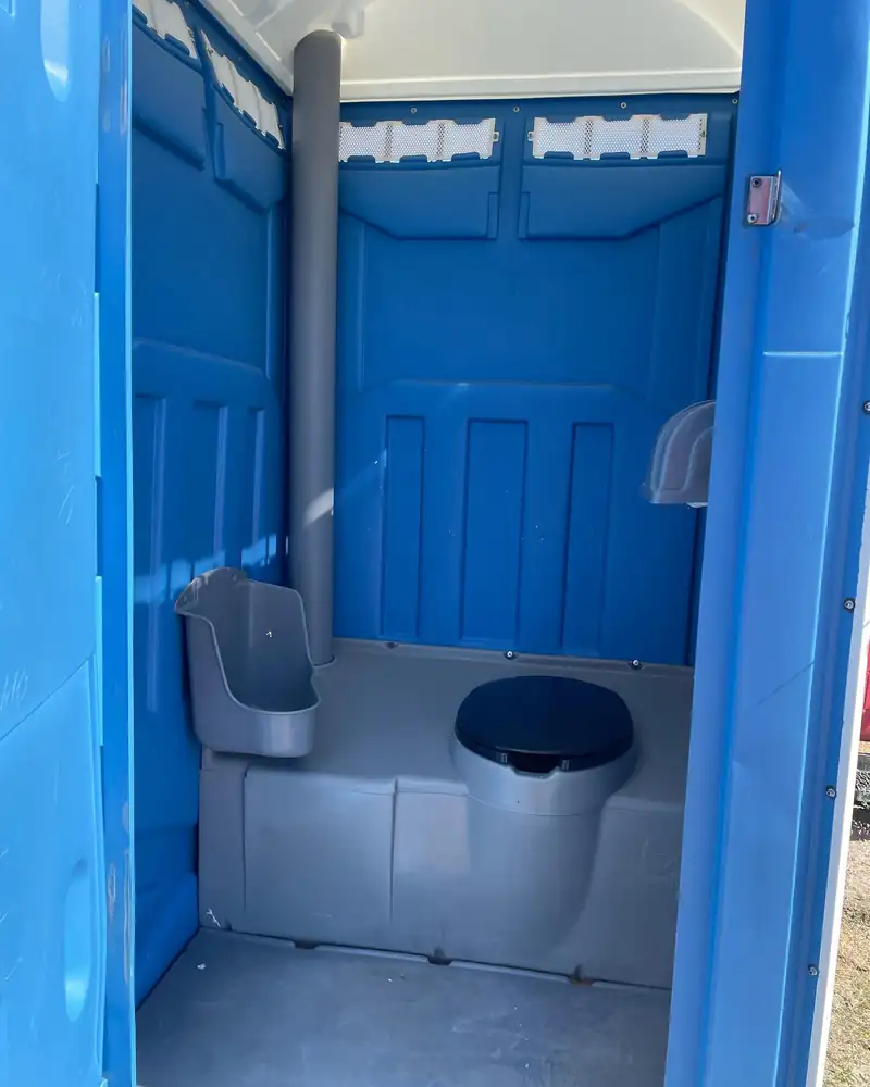 Urinal and seat inside a standard porta potty after weekly job site service in Midland, TX