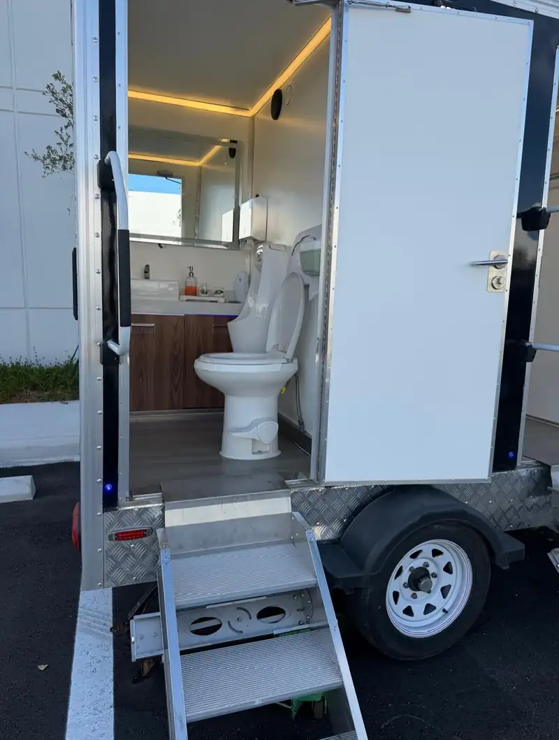 VIP single-suite restroom trailer with its door open at a ranch wedding near Midland, TX